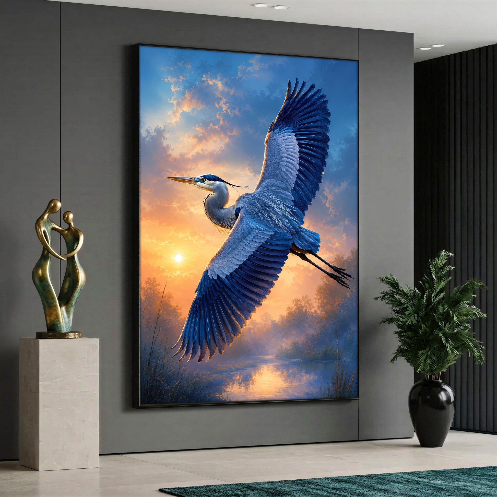 A vertical canvas print featuring a blue heron bird flying across a warm sunset sky over a calm river, displayed on a grey wall in a modern living room.