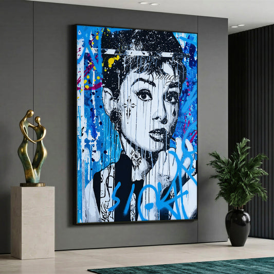 A pop art style canvas painting depicting a monochrome black and white portrait of Audrey Hepburn with a cross tattoo on her cheek and paint drips, featuring a prominent blue "Sick" graffiti text in front and a vibrant blue, yellow, and white street art background.