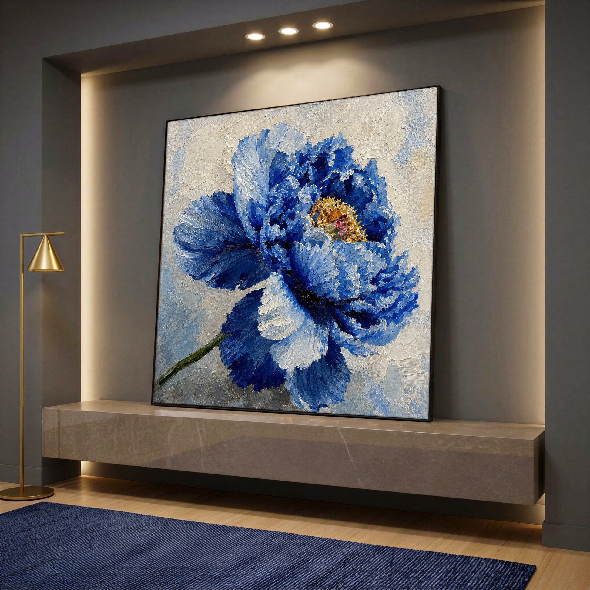 A square canvas wall art featuring a large, elegant blue peony flower with a golden center on a light background, displayed on a marble console shelf.